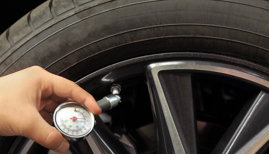 Hombre midiendo la presión de los neumáticos del coche con un manómetro, primer plano. Control de seguridad