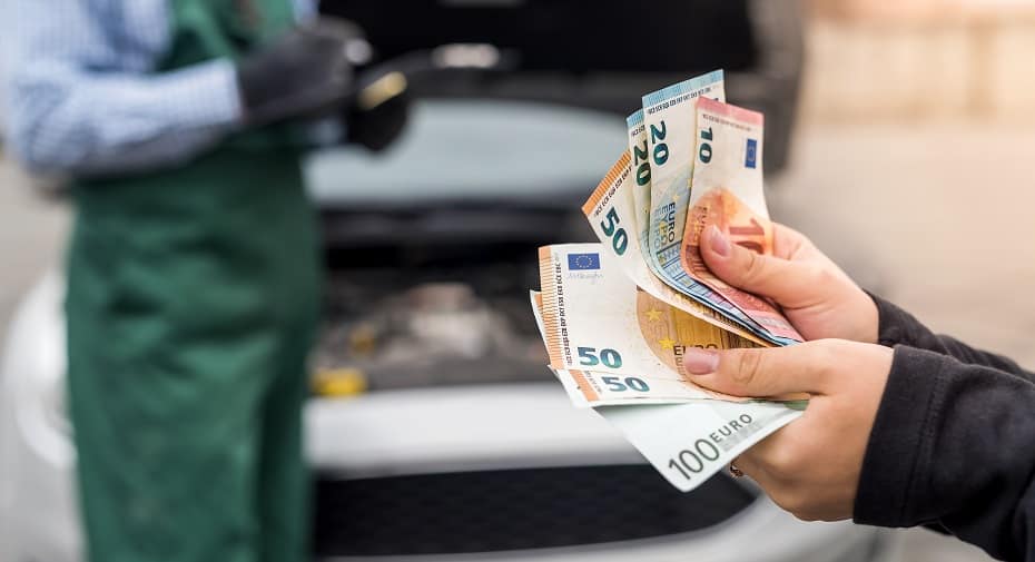 Billetes de euro en manos femeninas sobre fondo de motor de coche